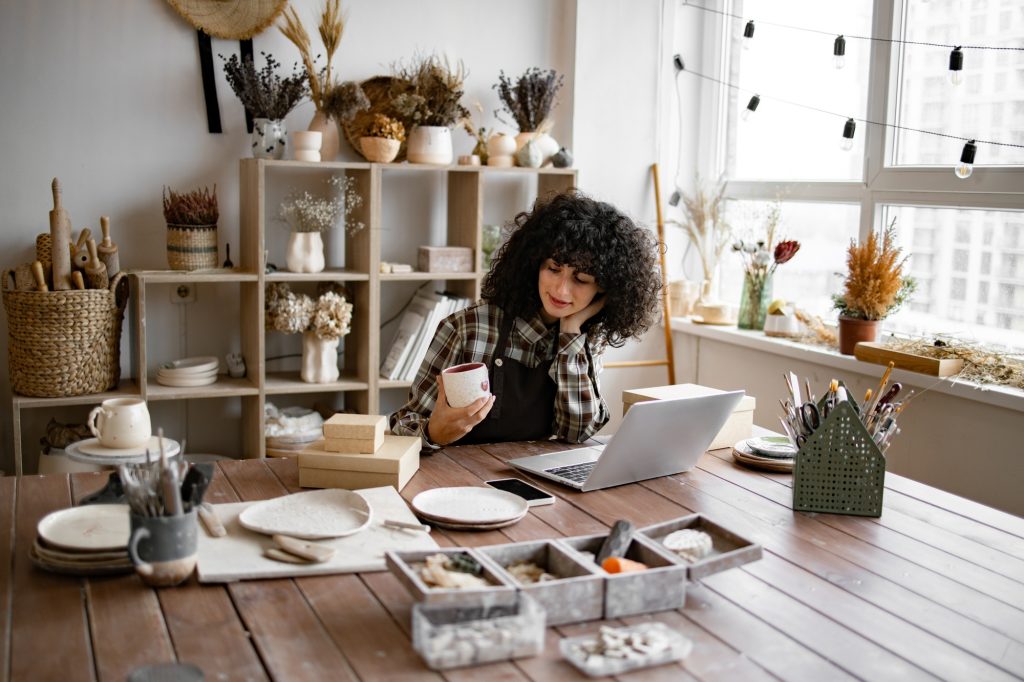 Female entrepreneur managing online order of mug on website.