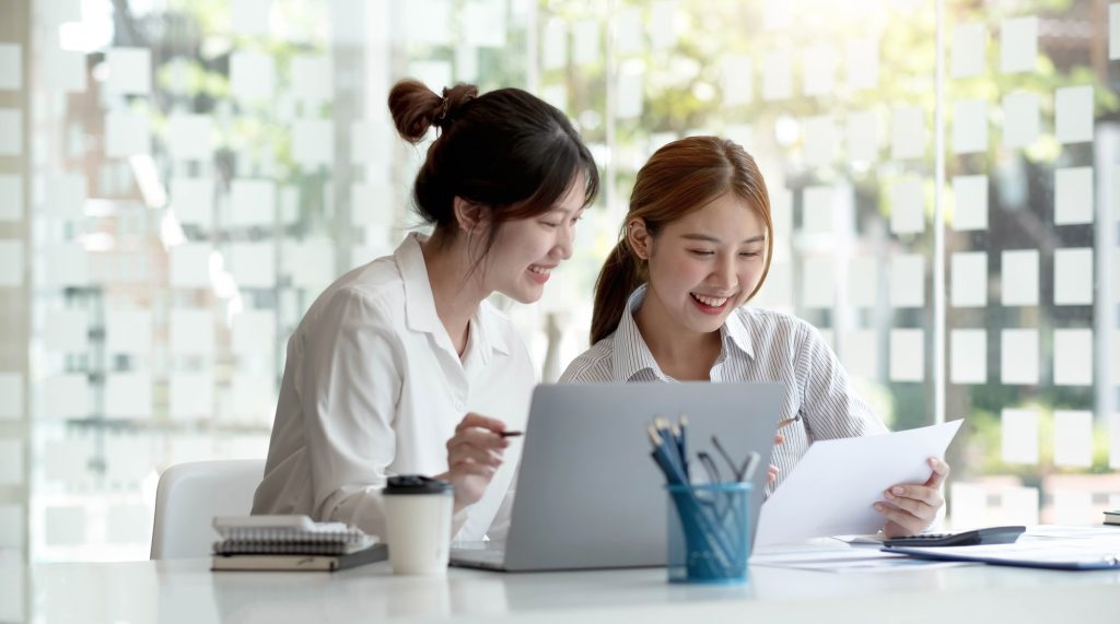 Two young Asian businesswoman discuss investment project working and planning strategy. Business